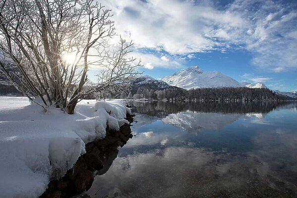 Snowcapped mountains reflected in the icy Lake Sils during a cold winter, Engadine, Canton of Graubunden, Switzerland, Europe