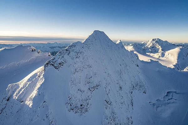 Snowcapped rock face of Monte Disgrazia and Piz Gluschaint in winter, aerial view