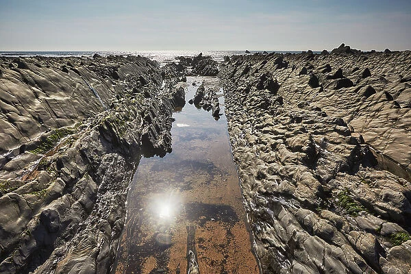 A sparkling sunlit shoreline pool on the Atlantic coast at low tide, Welcombe Mouth, a cove in the Hartland area of north Devon, England, United Kingdom, Europe