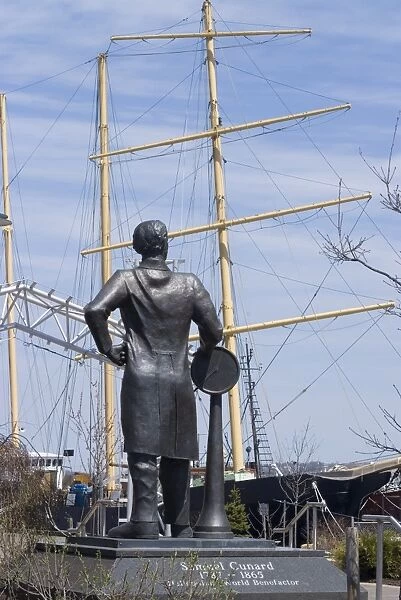 Statue of Samuel Cunard, native of Halifax, in front of tall ship on Harbour Walk