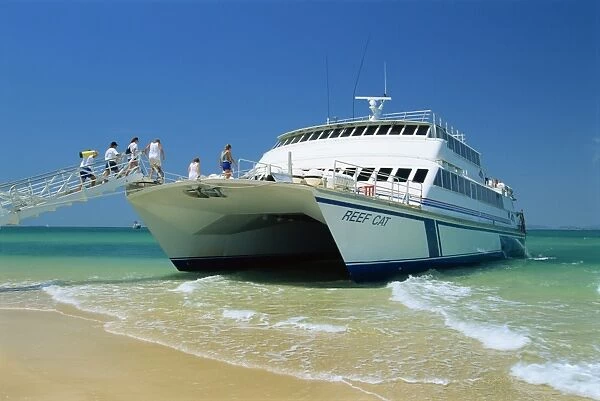 Tourists boarding large catamaran on beach near Rockhampton, Queensland