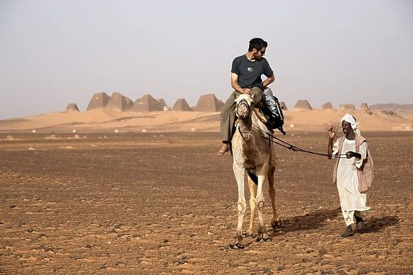 Tourists take camel rides at the pyramids of Meroe