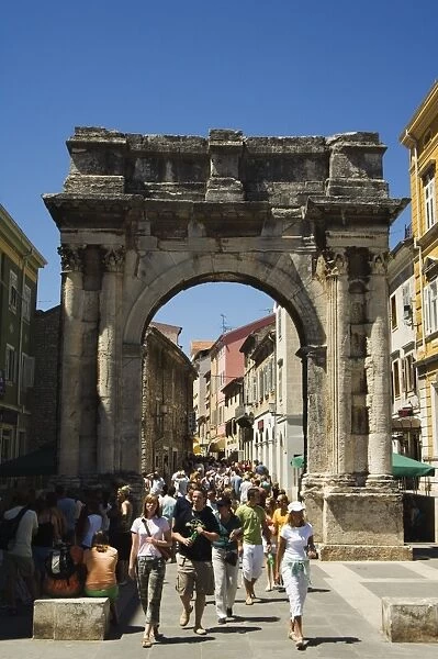 Tourists walking through stone arch in Old Town, Pula, Istria Coast, Croatia, Europe