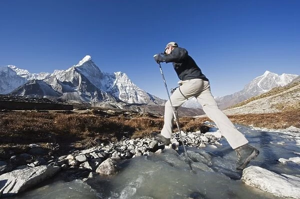 Trekker crossing a mountain stream, Ama Dablam, 6812m, behind, Solu Khumbu Everest Region