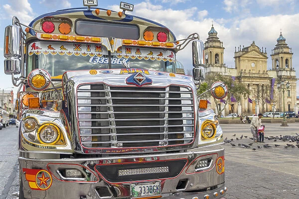A typical chicken bus standing at the main square of Guatemala City with view to