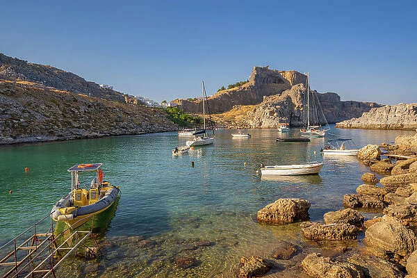 View of sailboats in St. Paul's Bay, Lindos, and Lindos Acropolis from beach, Lindos, Rhodes, Dodecanese Island Group, Greek Islands, Greece, Europe