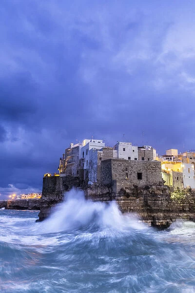 Waves crash on the cliff during a winter storm at dusk, Polignano a Mare, Apulia, Italy