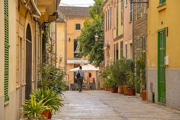 Woman walking down narrow street in the old town of Alcudia, Alcudia, Majorca, Balearic Islands, Spain, Mediterranean, Europe
