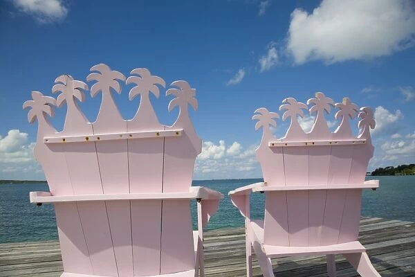 Wooden pink beach chairs with backs carved in the shape of palm trees