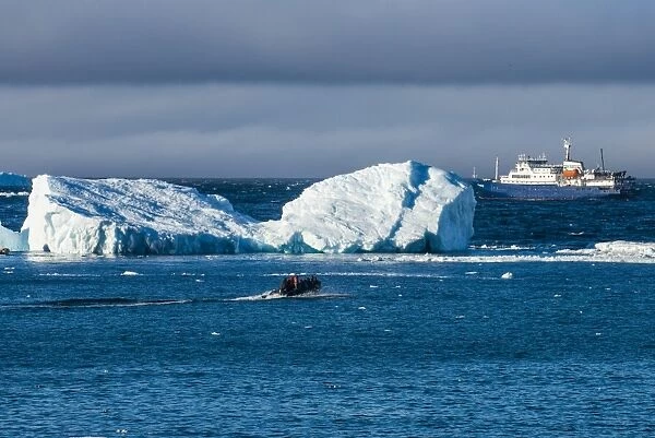 Zodiac cruising back to a cruise ship anchoring behind an iceberg, Brown Bluff, Antarctica