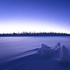 Arctic dusk lights over the frozen land covered with snow in winter, Lapland, Finland, Europe