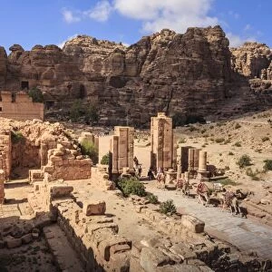 Camel train approaches Temenos Gateway with Qasr al-Bint temple, City of Petra ruins