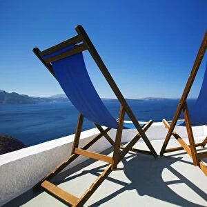 Deck chairs on terrace overlooking ocean, Santorini, Cyclades, Greek Islands, Greece, Europe