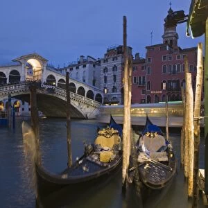 Gondolas moored on the Grand Canal at Riva del Vin, with Rialto bridge behind