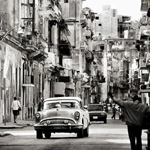 Image taken with a Holga medium format 120 film toy camera of view along busy street showing dilapidated buildings, old American cars and local people, Havana, Cuba, West Indies