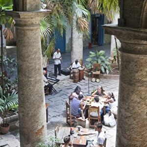 People sitting at tables and musicians playing in courtyard of colonial building built in 1780