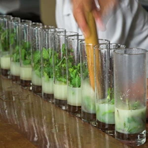 Row of glasses on a bar with barman preparing mojito cocktails, Habana Vieja