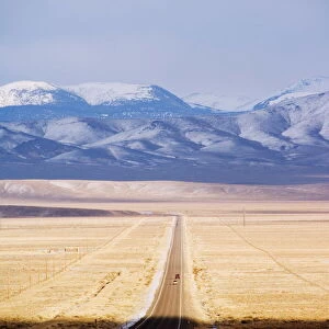 Snow capped mountains on a straight road of American south west, U