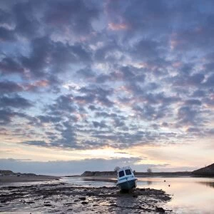 View towards Church Hill and the Aln Estuary during a stunning winter sunrise from the beach at low tide with a fishing boat in the foreground, Alnmouth, near Alnwick, Northumberland, England, United Kingdom, Europe