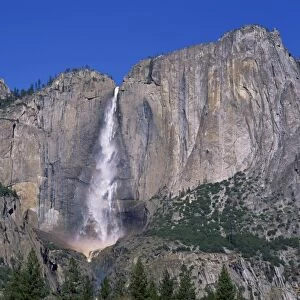 Waterfall cascades over rock wall at Rainbow Falls in the Yosemite Park