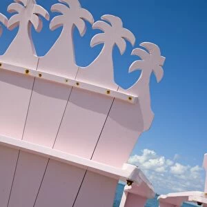 Detail of wooden pink beach chairs with backs carved in the shape of palm trees