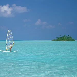 Young man windsurfing near tropical island and lagoon in the Maldives, Indian Ocean