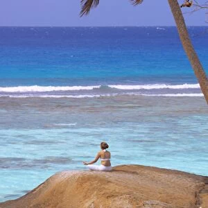 Young woman meditating on rock, Seychelles, Indian Ocean, Africa