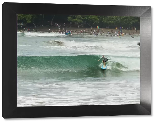 Surfer on a wave at this popular point break surf spot and small resort, Batu Karas, near Pangandaran, West Java, Java, Indonesia, Southeast Asia, Asia