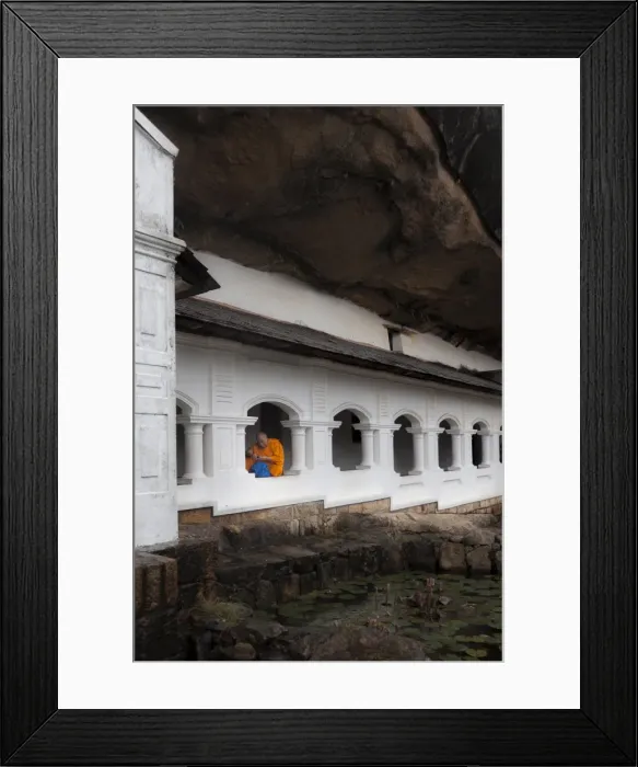 Framed Print : A monk sits and looks at his phone beneath shelter, Royal Rock Temple, Golden Temple of Dambulla, UNESCO World Heritage Site, Dambulla, Sri Lanka, Asia