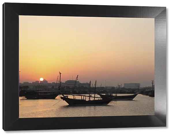 Traditional wooden dhow boats in the Corniche marina, at sunset in Doha, Qatar, Middle East