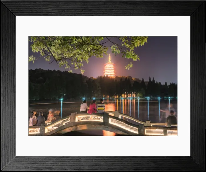 Framed Print : Leifeng Pagoda with visitors sitting on railings of an illuminated stone arch bridge at West Lake, Hangzhou, Zhejiang, China, Asia Framed Print : Leifeng Pagoda with visitors sitting on railings of an illuminated stone arch bridge at West Lake, Hangzhou, Zhejiang, China, Asia