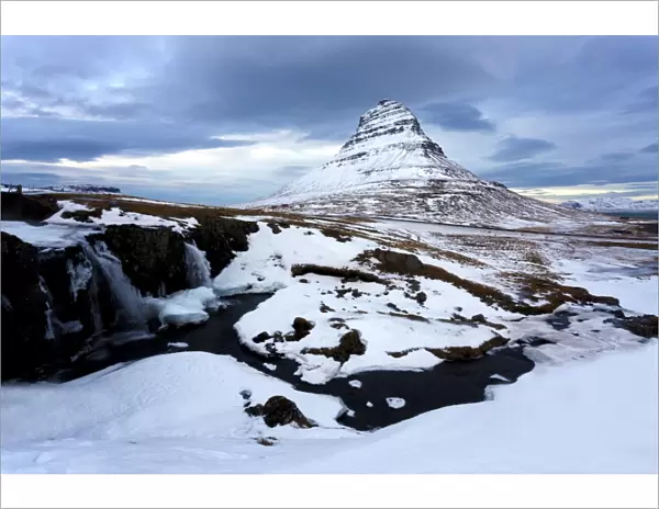 Kirkjufell (Church Mountain) covered in snow with a frozen river and waterfall in the foreground, near Grundarfjordur, Snaefellsnes Peninsula, Iceland, Polar Regions