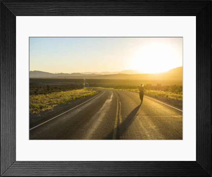 Framed Print : Woman walking down a long winding road at sunset in eastern Nevada, United States of America, North America
