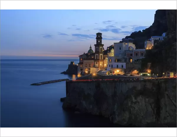 Amalfi coast road light trails from cars with Church of Santa Maria Maddalena at blue hour