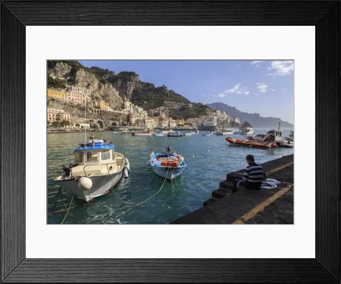 Framed Print : Fisherman working on harbour quayside with view towards Amalfi town and fishing boats Framed Print : Fisherman working on harbour quayside with view towards Amalfi town and fishing boats