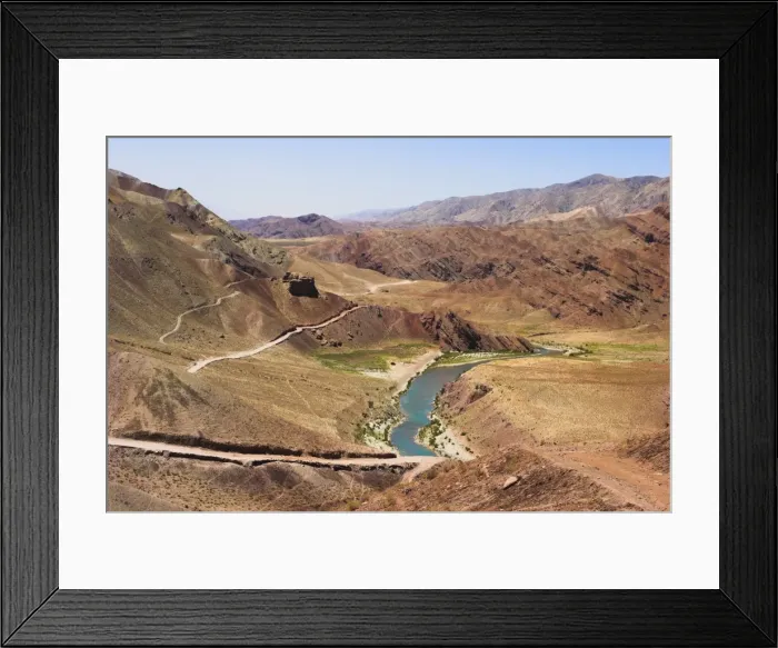 Framed Print : Hari Rud river flowing through fertile valley at base of red rock mountains Framed Print : Hari Rud river flowing through fertile valley at base of red rock mountains