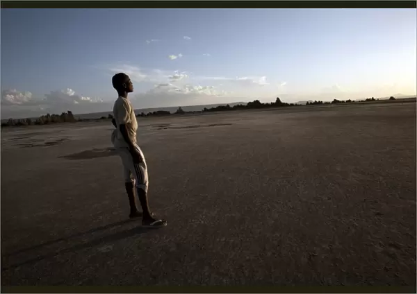 A boy stands in the desolate landscape of Lac Abbe, Djibouti, Africa