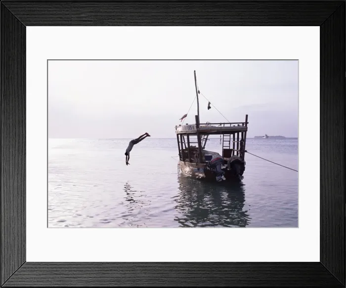 Framed Print : Boy in mid-air diving from a boat moored by the beach at Stone Town, island of Zanzibar Framed Print : Boy in mid-air diving from a boat moored by the beach at Stone Town, island of Zanzibar