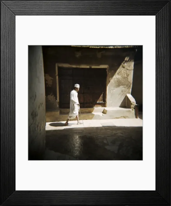 Framed Print : Old man walking down shady street in traditional white robes, Stone Town Framed Print : Old man walking down shady street in traditional white robes, Stone Town