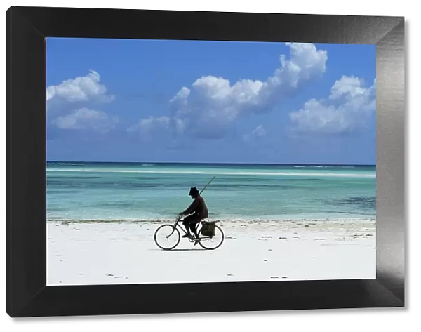 A man riding his bicycle of Kiwengwa beach, island of Zanzibar, Tanzania