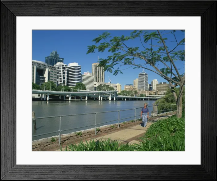 Framed Print : Tourist walking beside the Brisbane River and the city skyline behind, Brisbane Framed Print : Tourist walking beside the Brisbane River and the city skyline behind, Brisbane