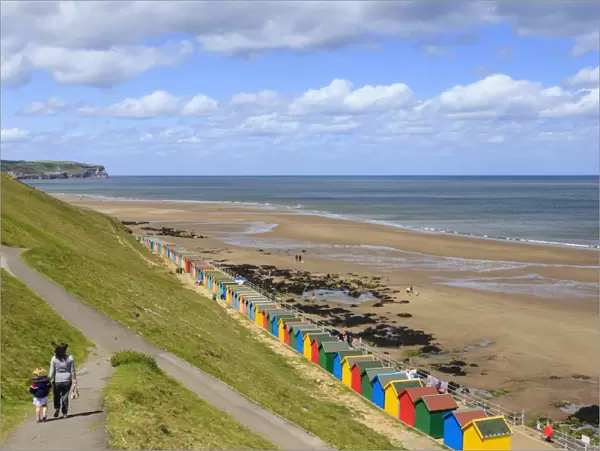 Elevated view of colourful beach huts on West Cliff Beach, mother and daughter hand in hand