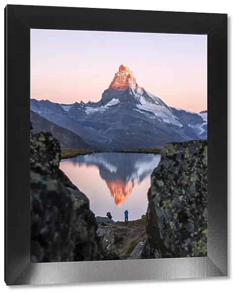 Hikers admire the Matterhorn reflected in the Stellisee at sunrise, Zermatt, Canton of Valais