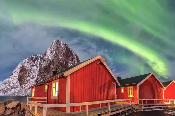 The green light of the Northern Lights (aurora borealis) lights up fishermans cabins