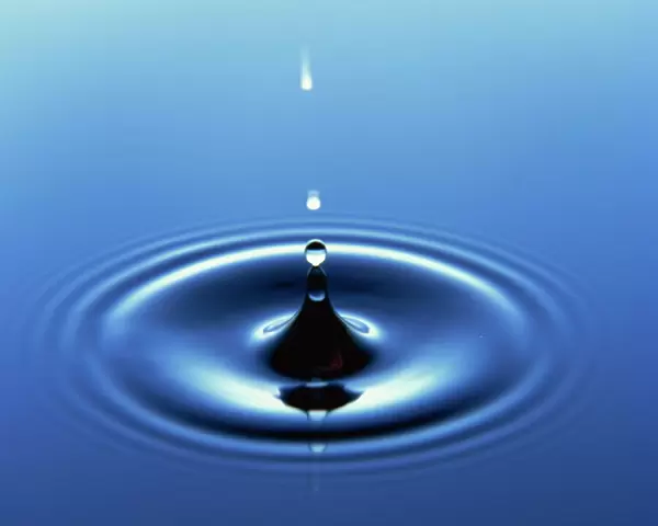Water droplet hitting water surface creating ripples