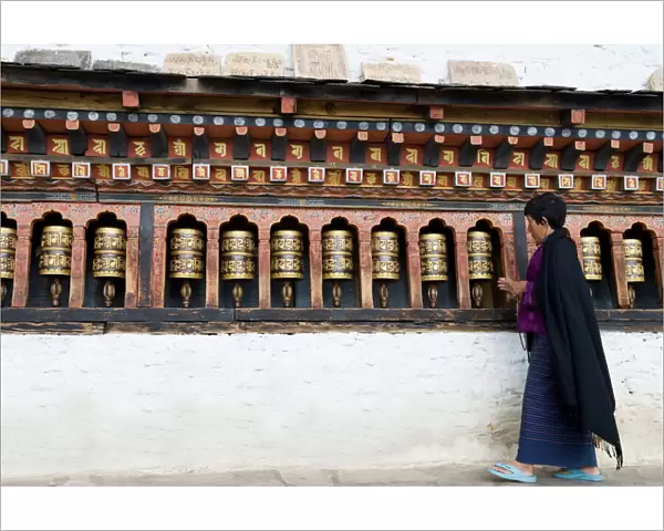 Bhutanese woman turning Buddhist prayer wheels, Trashi Chhoe Dzong, Thimphu, Bhutan, Asia