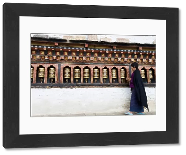 Bhutanese woman turning Buddhist prayer wheels, Trashi Chhoe Dzong, Thimphu, Bhutan, Asia
