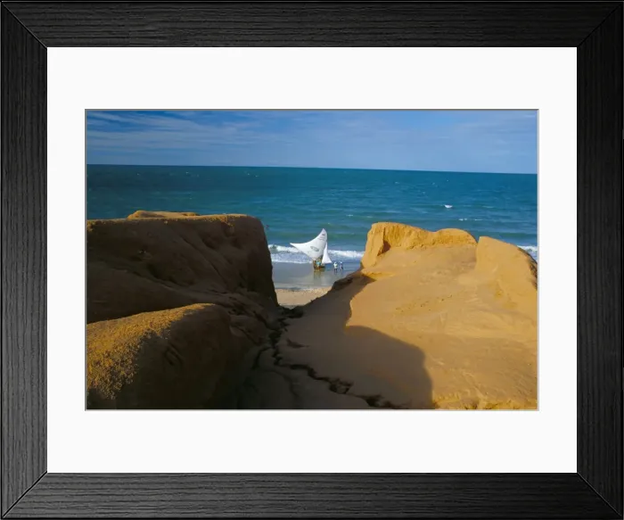 Framed Print : Red rock formations and jangada boat on the seafront of Canoa Quebrada
