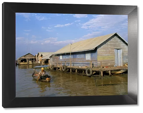 Man in canoe passing a house, floating fishing village of Chong Kneas, Tonle Sap lake