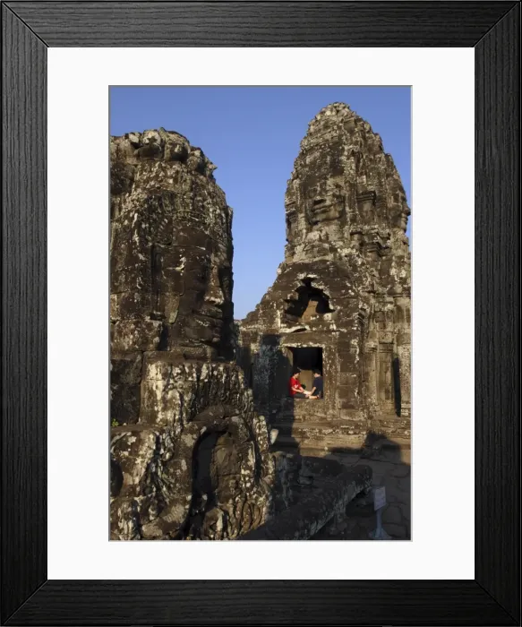 Framed Print : A couple rest beneath the giant faces of the Bayon temple, Angkor, UNESCO World Heritage Site Framed Print : A couple rest beneath the giant faces of the Bayon temple, Angkor, UNESCO World Heritage Site